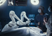 Two Surgeons Observing High-Precision Programmable Automated Robot Arms Operating Patient In High-Tech Hospital. Robotic Limbs Performing Complicated Nanosurgery, Doctors Looking At Vitals On Monitor.