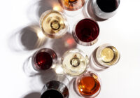 Red, rose and white wine in glasses on white background, top view. Wine bar, shop, winery, wine tasting concept. Hard light and harsh shadows